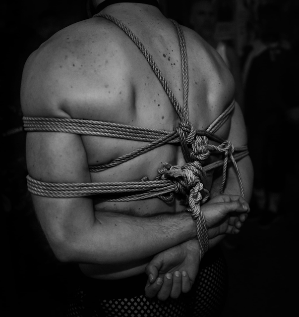 Rope harness knotted tight across a bound back